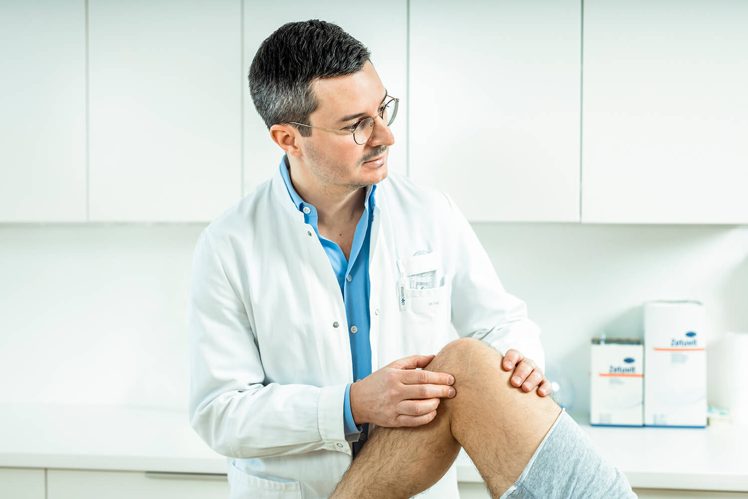 Dr. Figl in seiner Ordination untersucht ein verletztes Knie eines Patienten